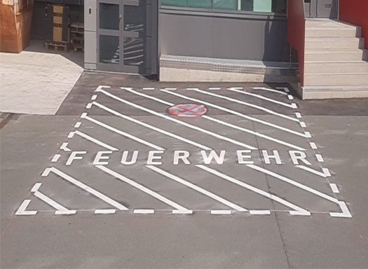 Parkplatz mit der Aufschrift „FEUERWEHR“ in großer, auffälliger Schrift.