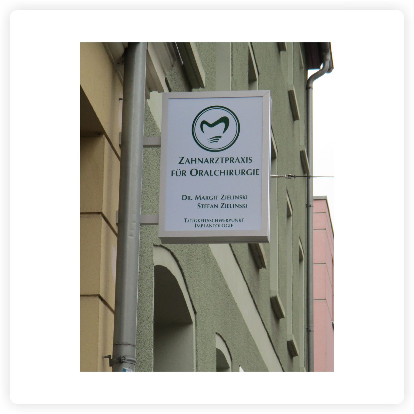 Ausleger-Leuchtkasten für Arztpraxis Beschrifteter Ausleger-Leuchtkasten mit Logo und Praxisangaben an der Fassade einer Zahnarztpraxis