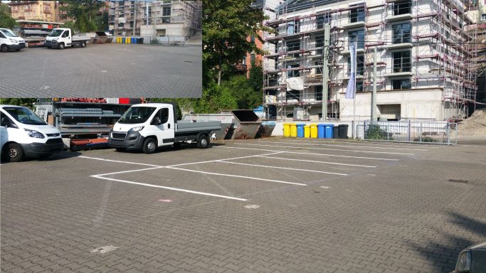 Neu markierte Parkflächen mit weißen Linien auf gepflastertem Parkplatz eines Gewerbeareals