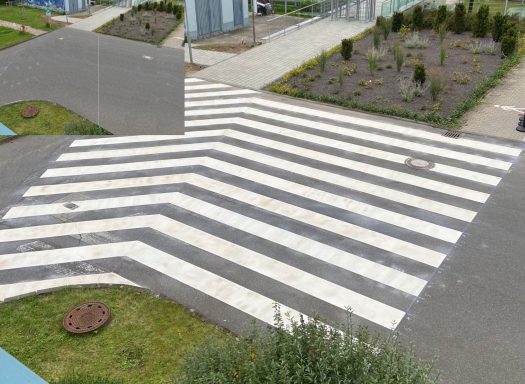 Weiße Zebrastreifen-Markierung auf asphaltierter Verkehrsfläche zur sicheren Fußgängerführung auf einem Firmengelände.