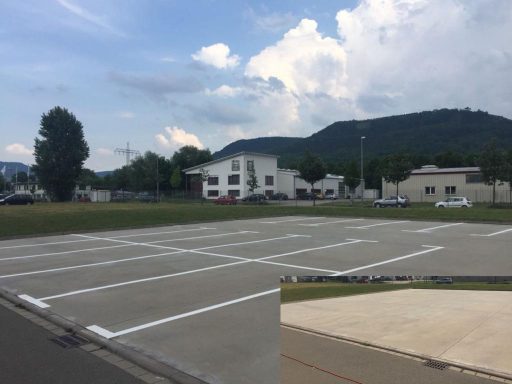Weiße Parkplatzmarkierungen auf großem Außenparkplatz aus Beton mit mehreren Stellflächen